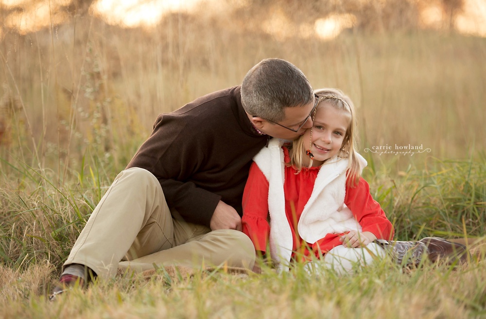father_kissing_daughter_in_field_at_sunset
