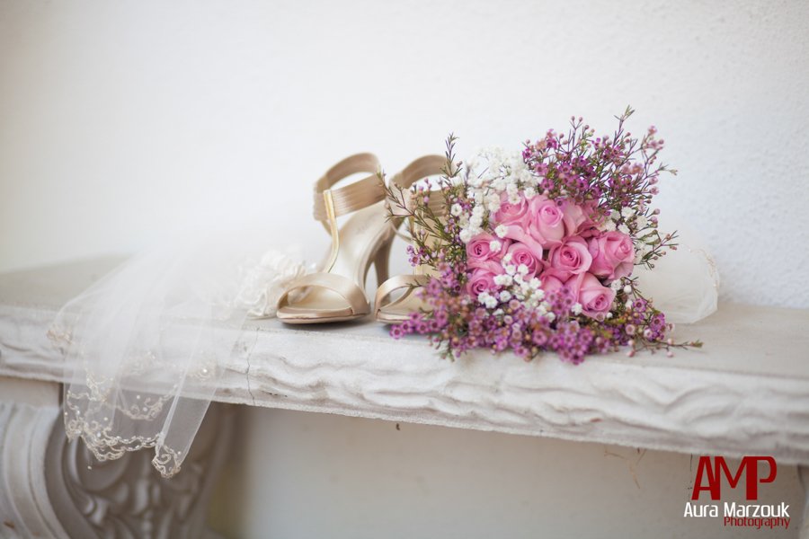 Bride's gorgeous gold shoes and pink rose bouquet next to a beauitful white veil. © Aura Marzouk Photography