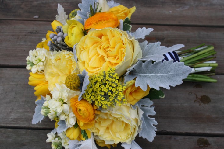 Yellow roses, ranunculus, cream stock, freesia, silver brunia and dusty miller bridal bouquet