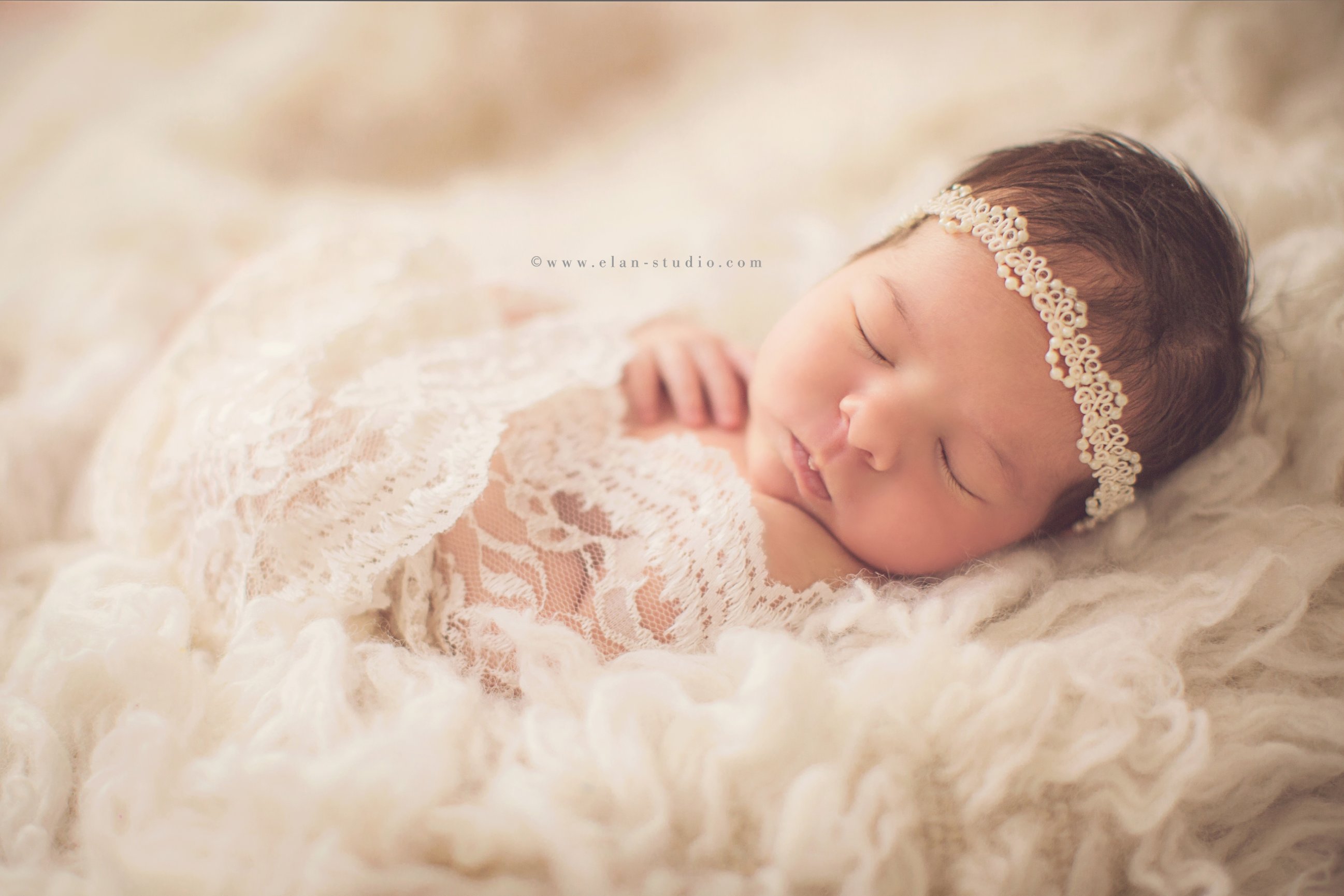 newborn in lace wrap with pearl headband