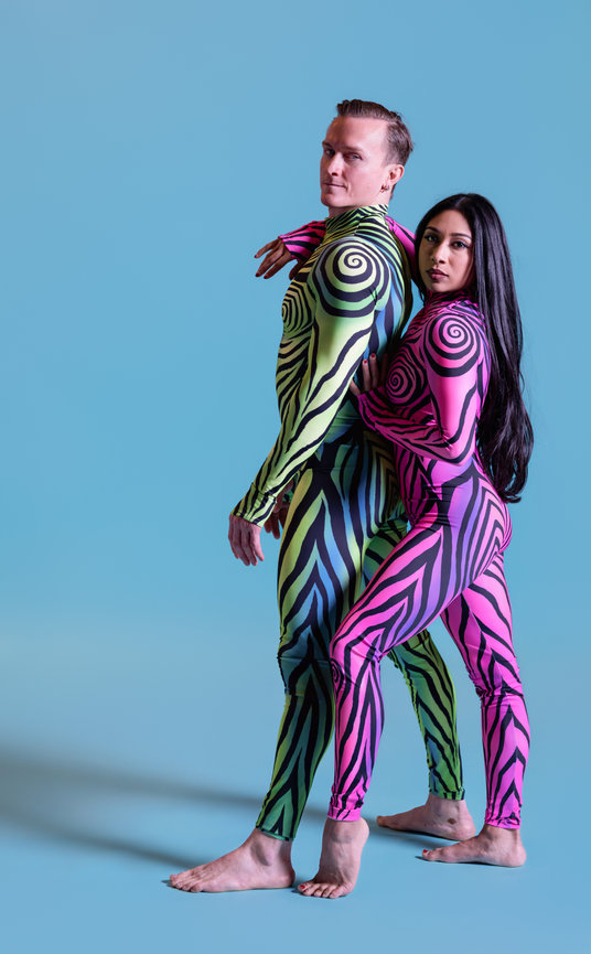 Two performers in colorful body suits posing against a blue background