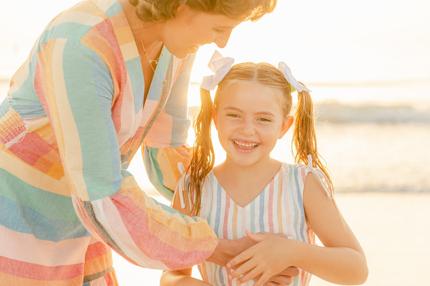 cancer survivor smiling at her young daughter who has pigtails and bows in her hair