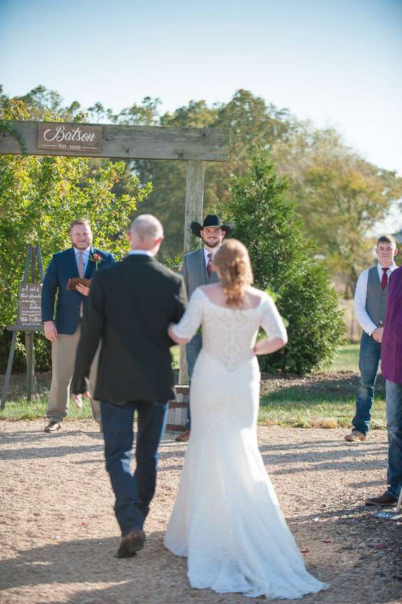 Groom smiling at his bride as she walks down the aisle to be married.