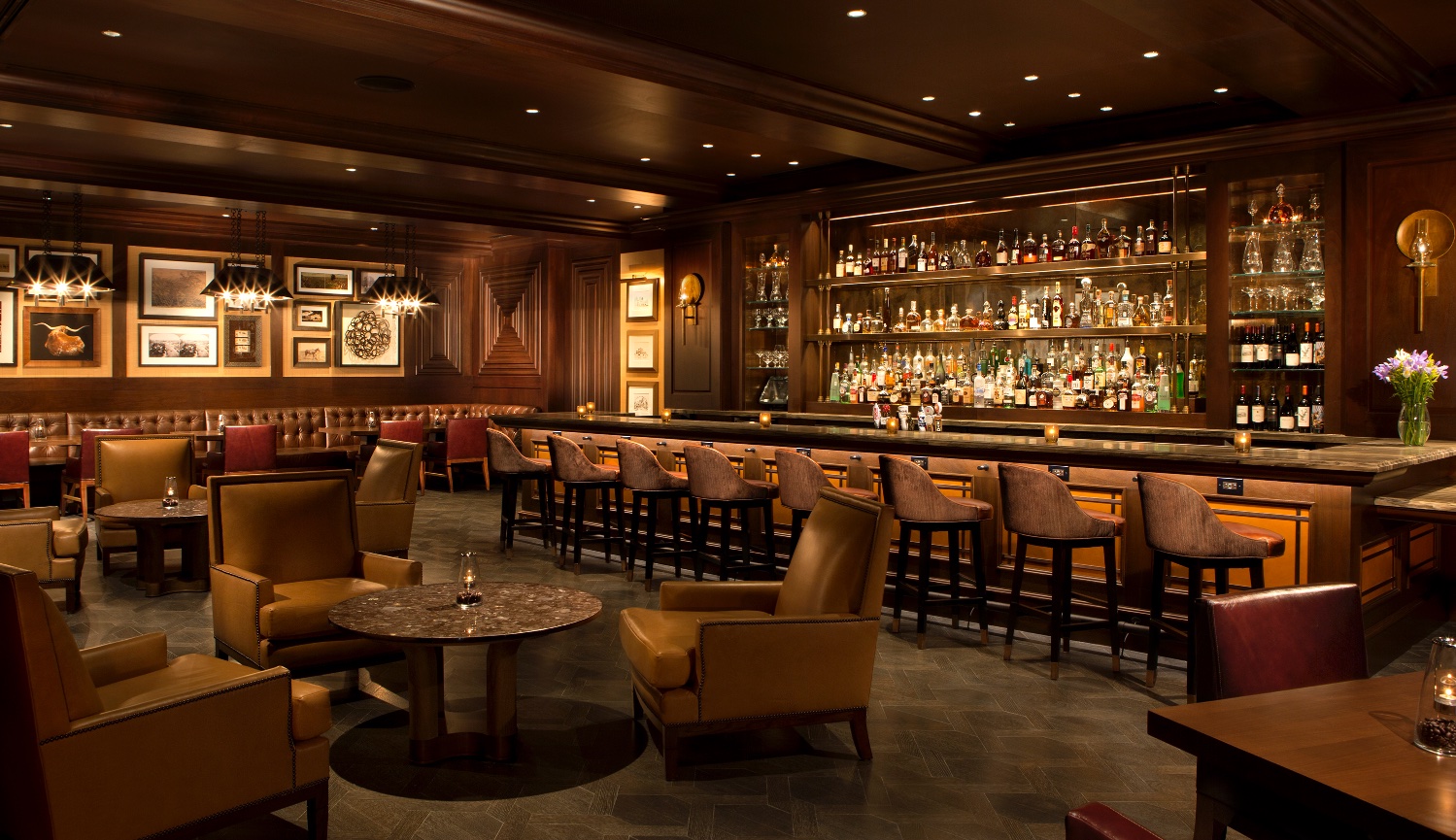 Modern beautifully lit Bar and Restaurant in a large space with Dark wood ceilings and dark marble floors at The La Canterra Resort in Texas.