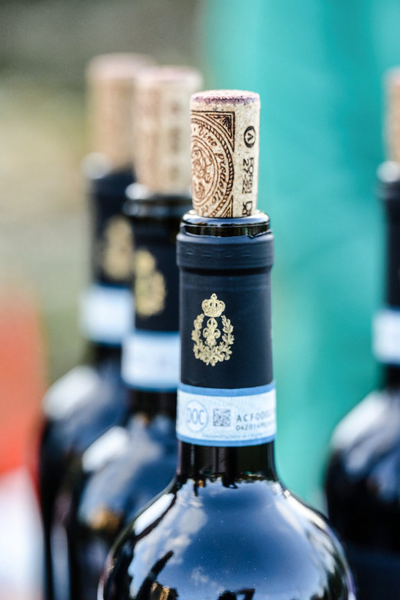 Close-up of wine bottles with corks, featuring ornate labels and blue seals.