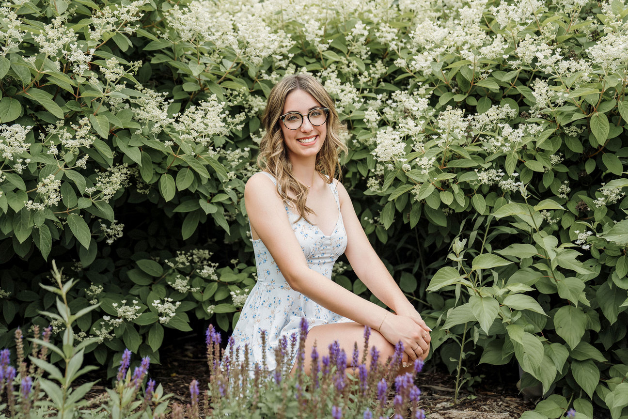 Senior portrait of girl in tree of white flower wearing a blue dress in Plymouth Minnesota