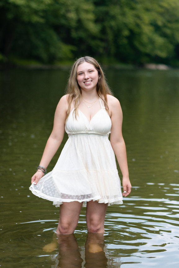 senior girl wearing a pastel dress splashing in a creek near Pittsburgh PA