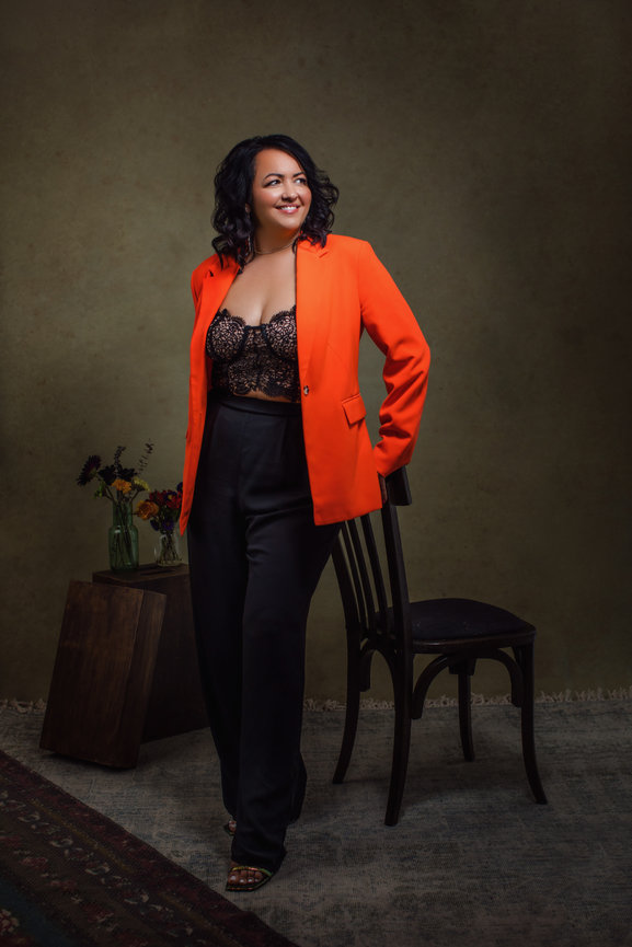 Beautiful and professional portrait of Christina Vela in orange blazer and sexy lace top, taken in a photo studio with Adam Trujillo, a Las Vegas portrait photographer.