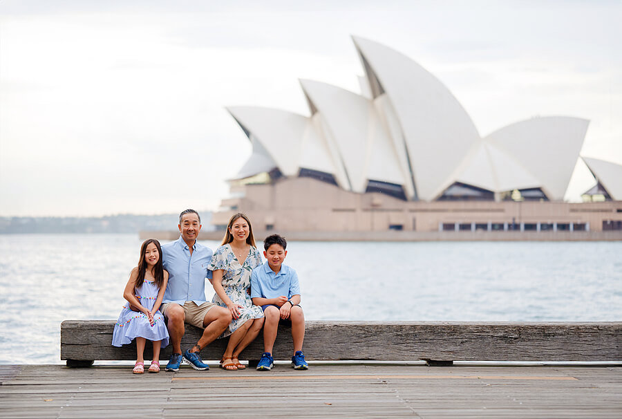 Portrait of a family sitting with Sydney Opera House behind them.