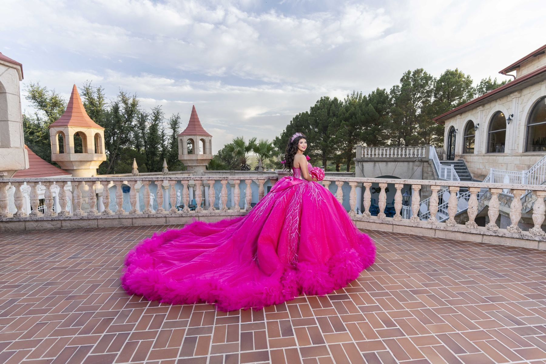 Quinceañera in a pink ball gown on a castle terrace