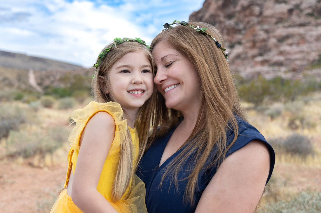 Smiling mother and daughter hugging outdoors in a rocky desert landscape