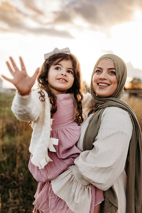 a woman in a hijab holds her daughter who reaches for the camera in a Huntsville, Alabama family photoshoot