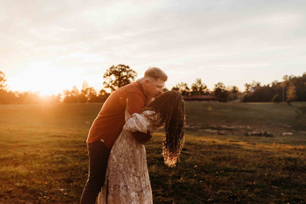 A man kisses his wife in front of the sunset in a Huntsville Alabama family photoshoot