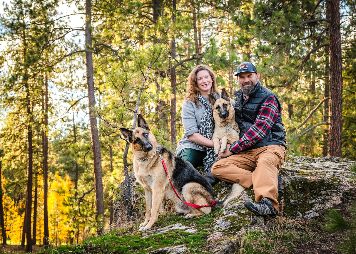Couple with two dogs in a park in Post Falls, Idaho, dogs secured on leash before editing.