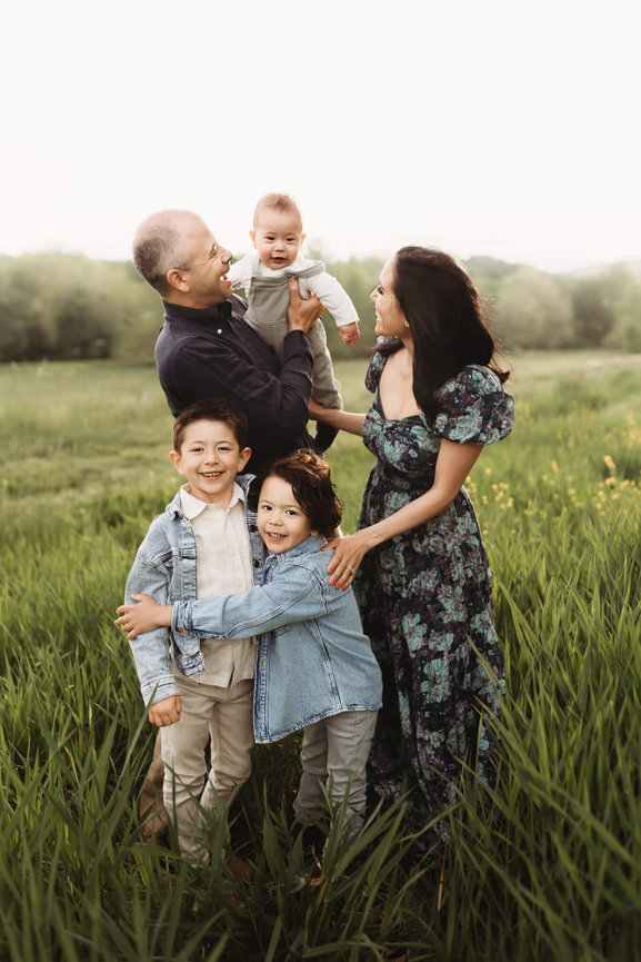 A family standing in a green field at the Central Park of Morris County, New Jersey.