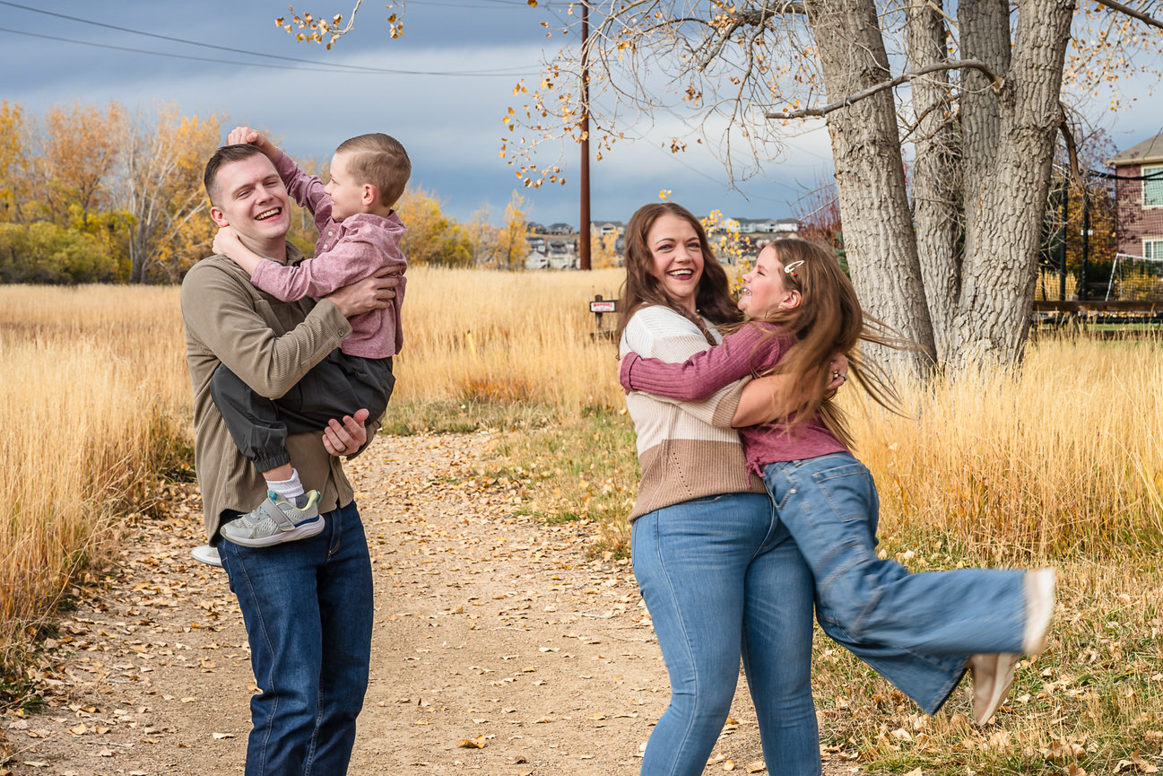 Two children have run in to the arms of their parents. The boy is giving the father noogies.