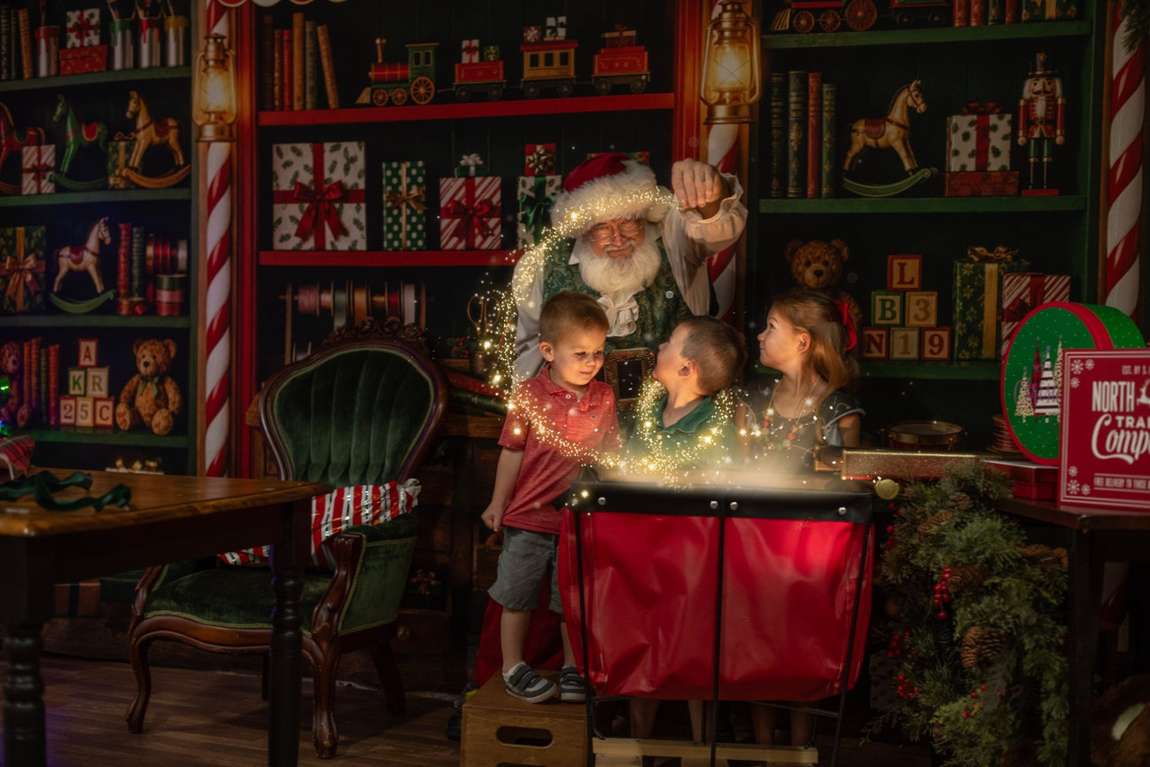 Santa and children discovering a glowing gift at Santa’s Magical Wrapping Station