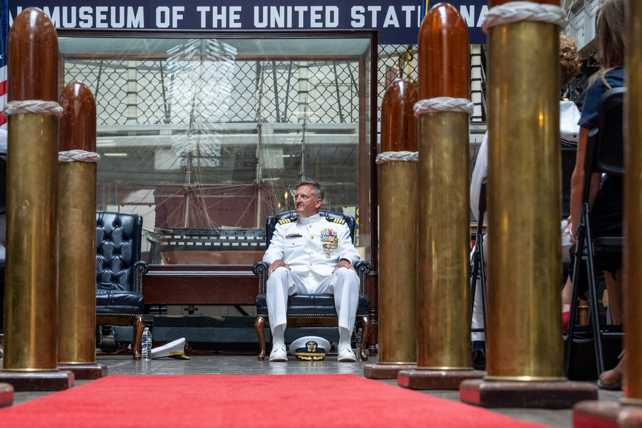 Naval Officer sitting at his retirement ceremony with red carpet and bullets in the foreground