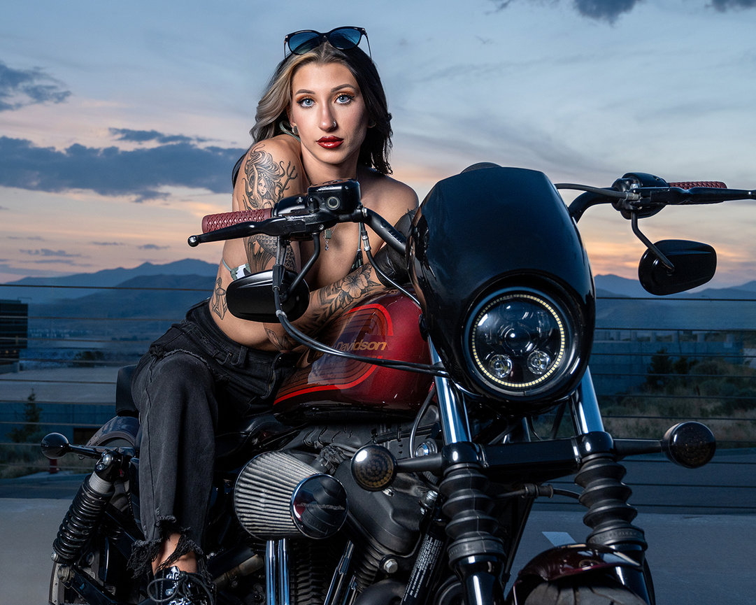 Tattooed model leaning confidently on a Harley-Davidson motorcycle during a sunset photoshoot in Lehi, Utah. Captured by Tre Nelson Photo.