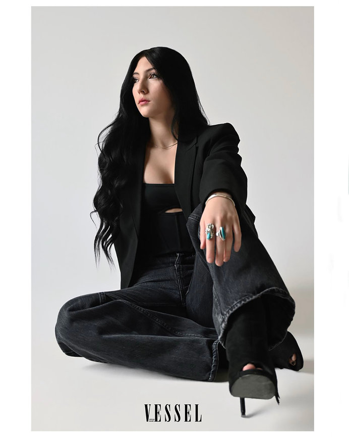 A professional branding portrait of a woman sitting confidently in black attire, featured in Vessel Magazine, based in Salt Lake City, Utah. Empowering businesswomen and entrepreneurs. Captured by Tre Nelson Photo.