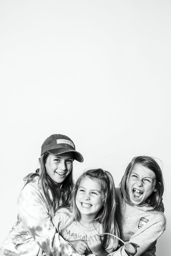 Three young girls, laughing and wearing casual clothes in black and white done by Newport Beach Photographer Chasing Poppies