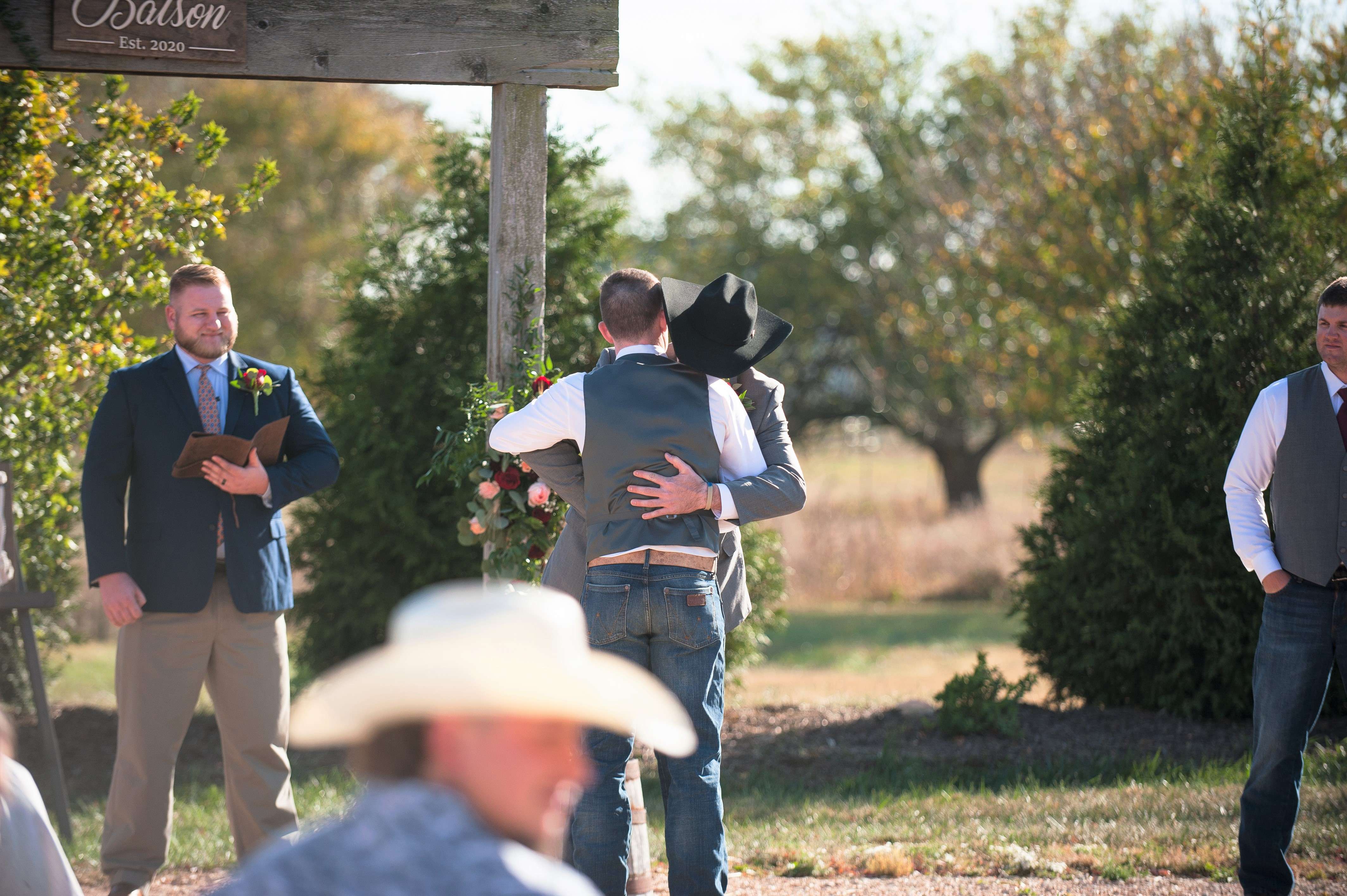 Best man and groom hug during wedding ceremony.