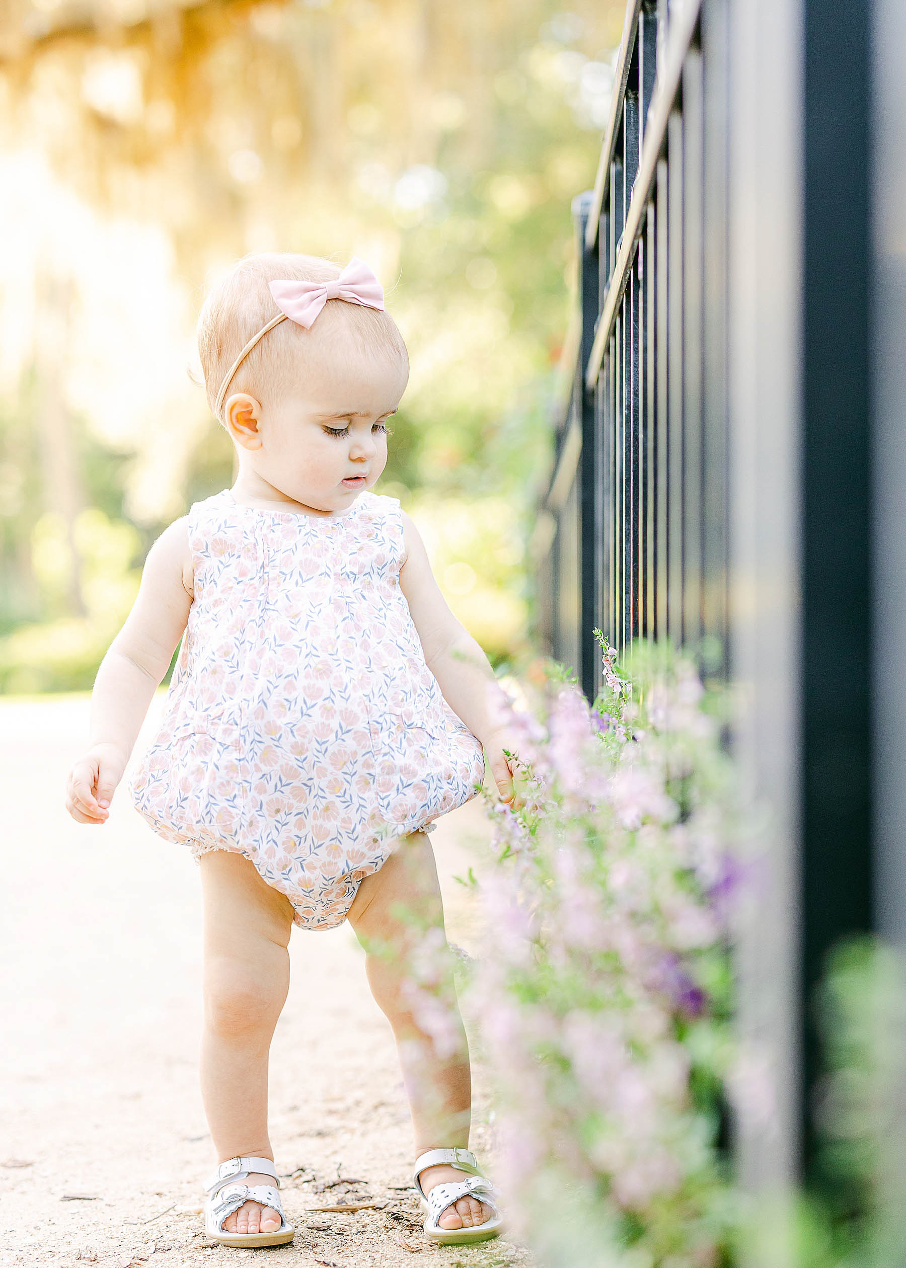 baby girl smelling flowers in the garden sunshine