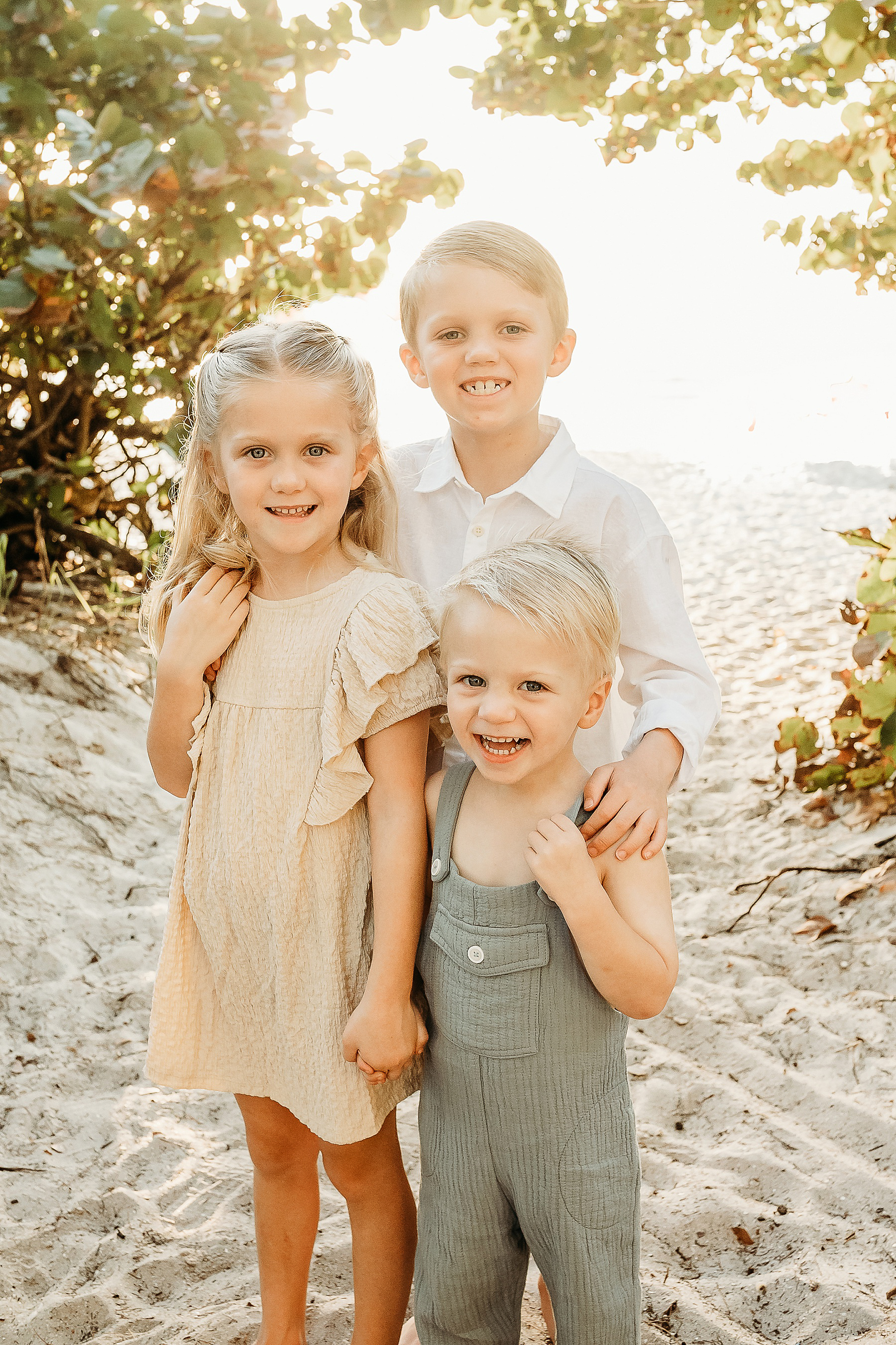 three children in Naples Florida smiling on the beach at Wiggins Pass