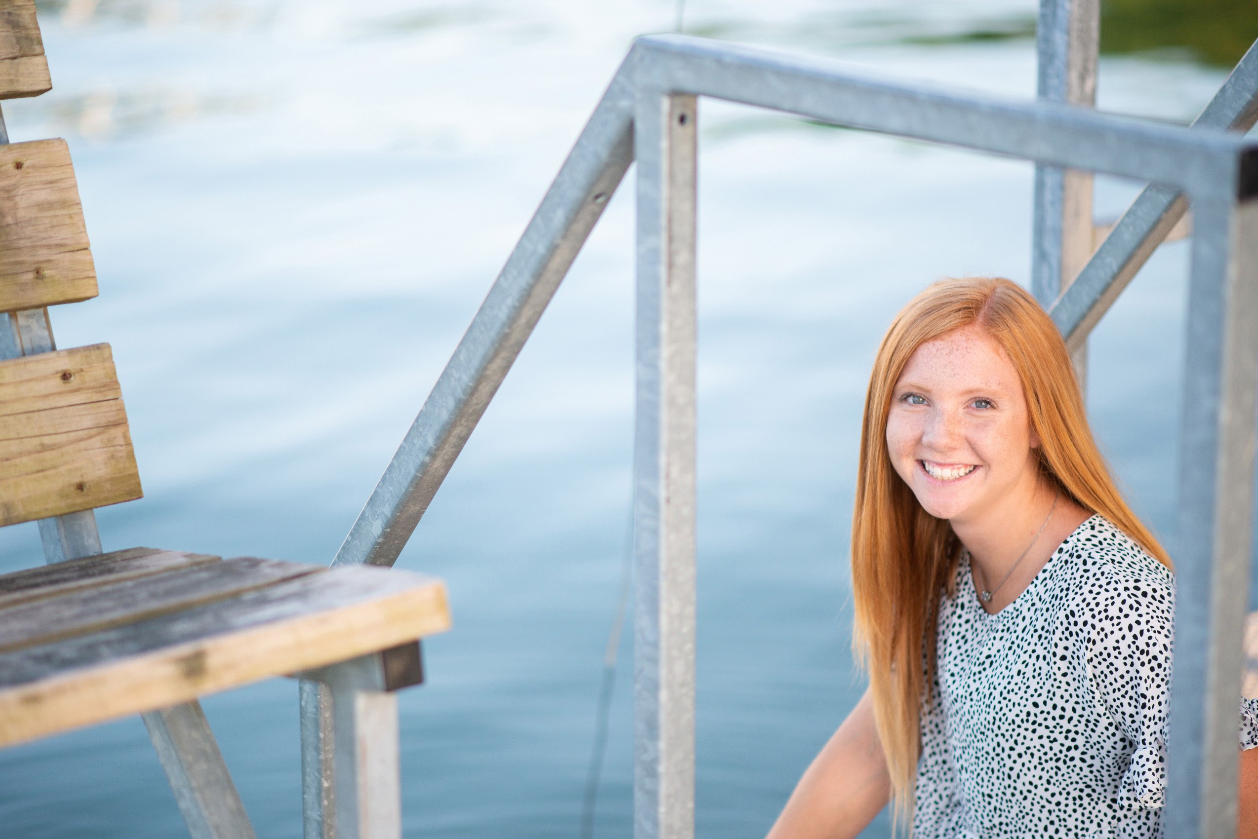 Senior girl in print top smiling for photos at Tablerock Lake dock.