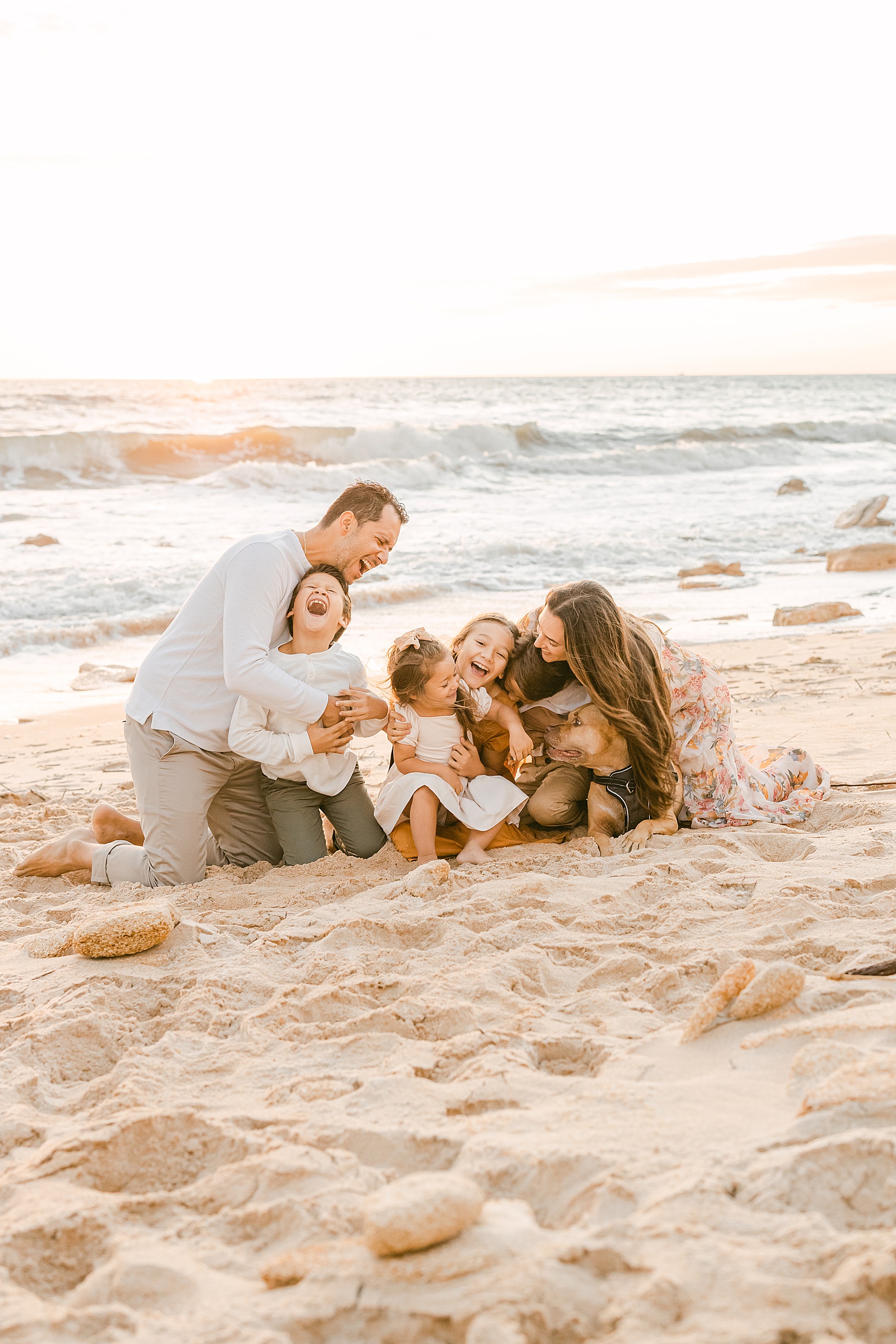 family sitting laughing on the beach at sunrise