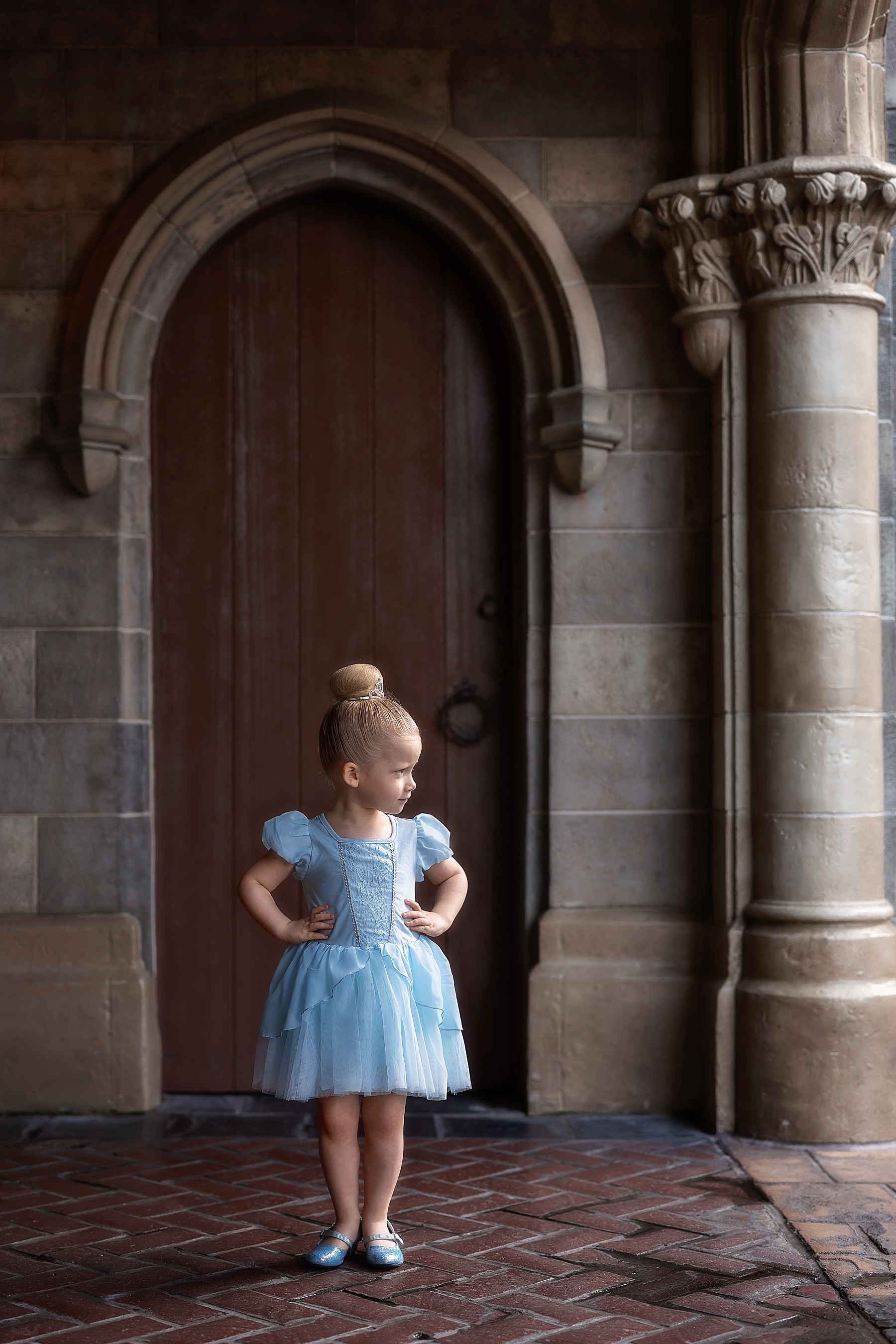 little girl at Walt Disney World Magic Kingdom standing by the castle in blue Cinderella dress