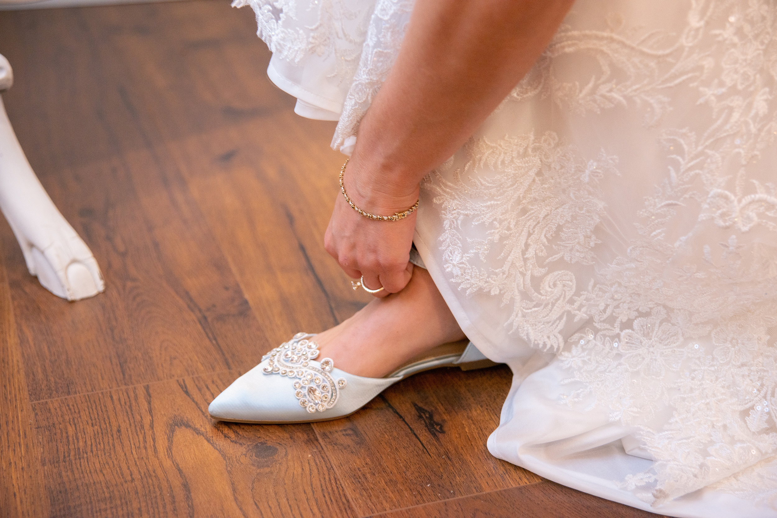 Bride putting blue shoes on while getting ready for her wedding.