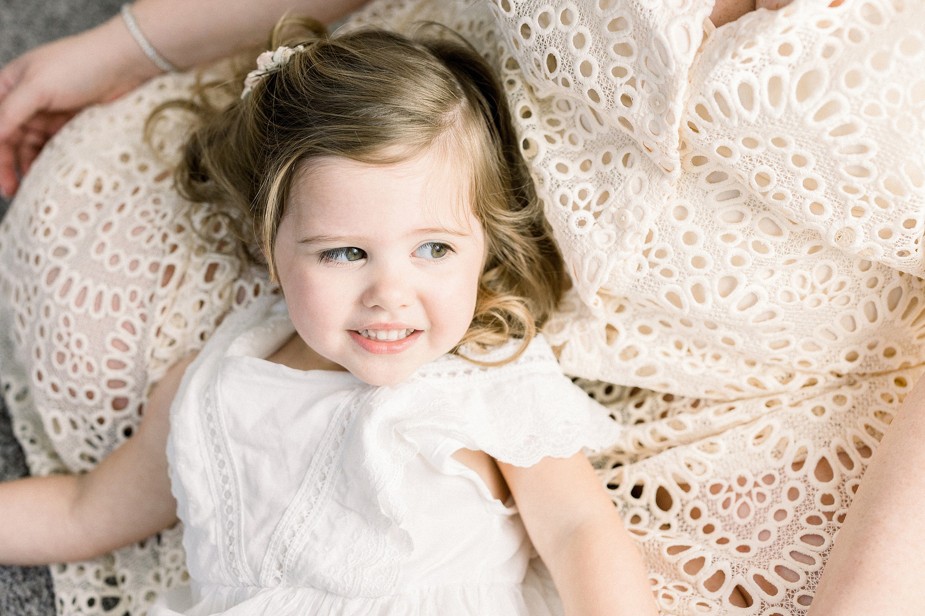 airy image of little girl in white lace dress laying by window