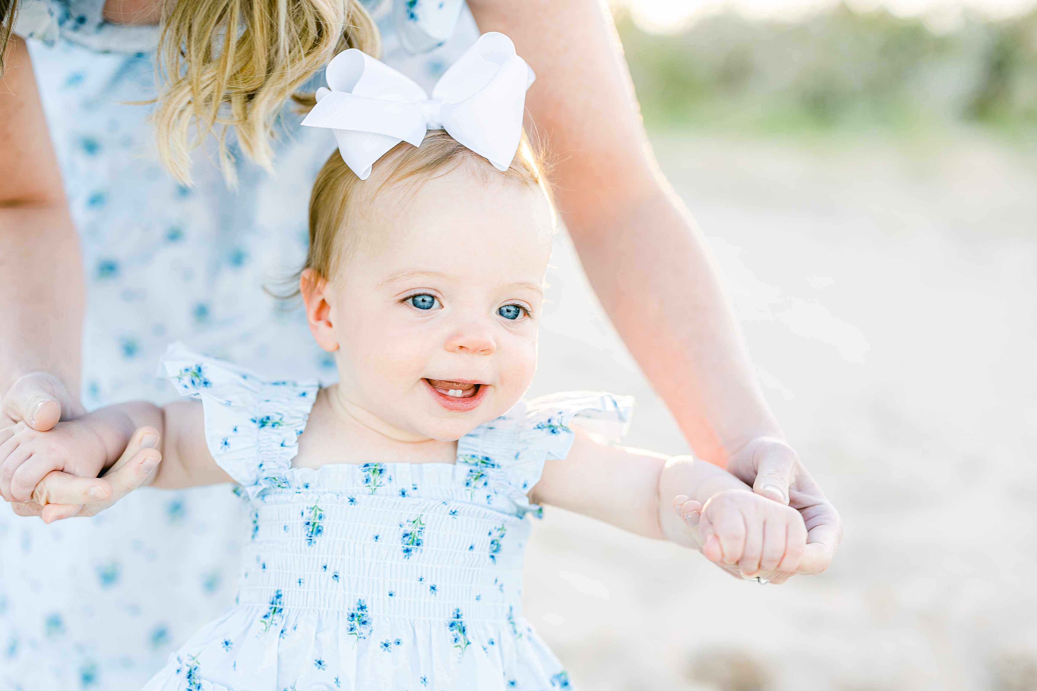 blue-eyed baby girl in blue and white floral dress smiling