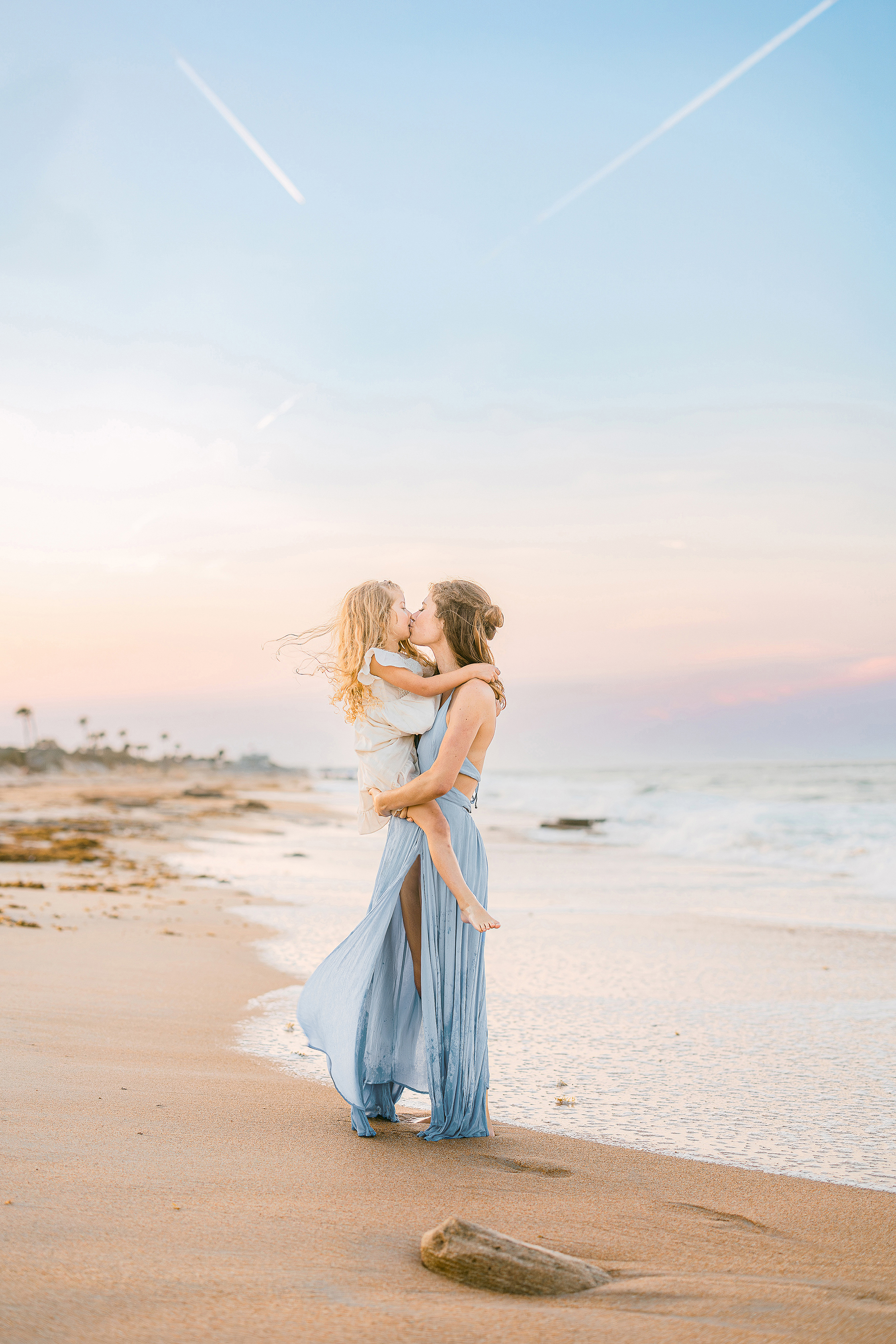 woman holding little girl at sunset on the beach with pastel skies in St. Augustine