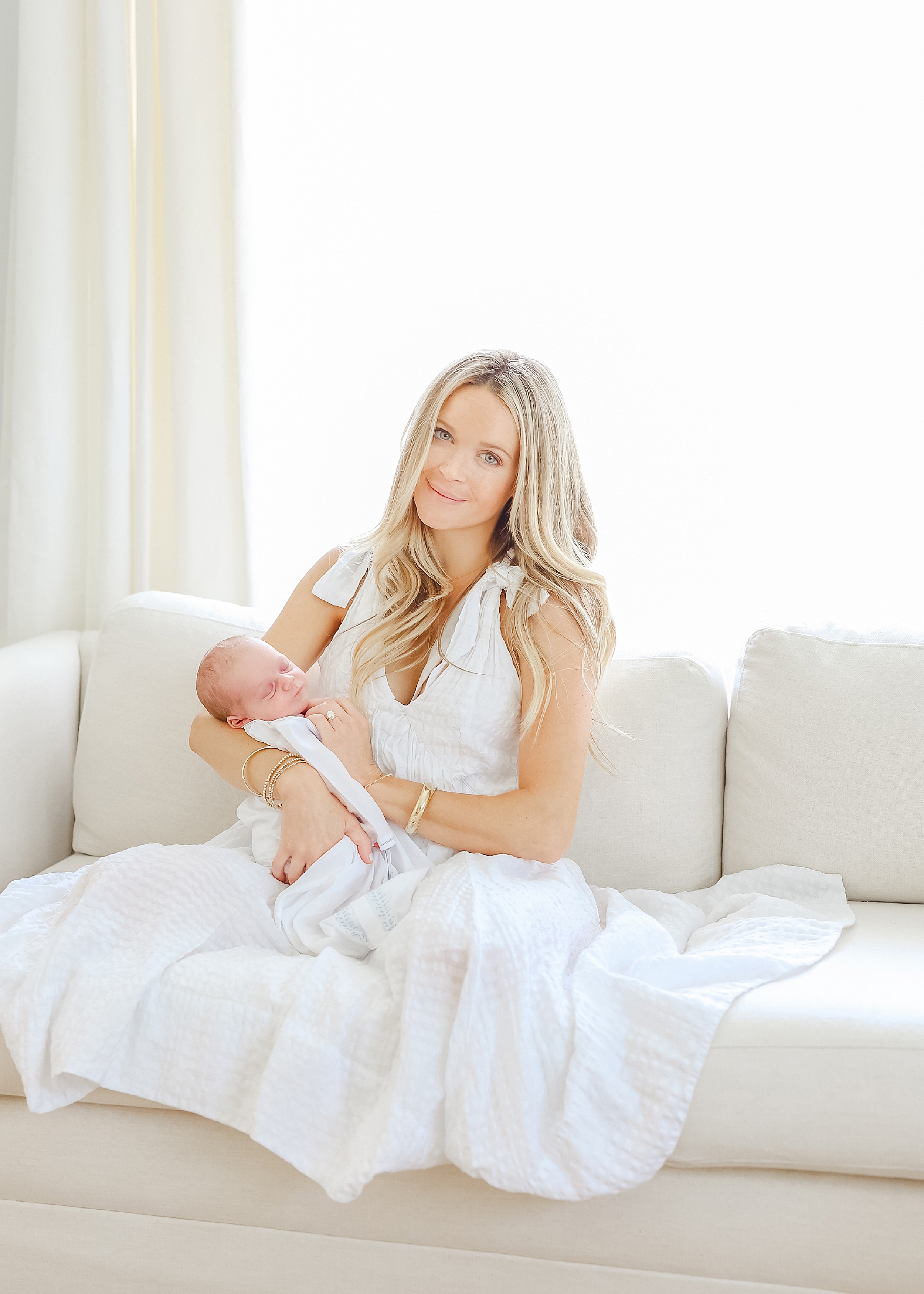 Airy newborn portrait of a mother holding her newborn son all dressed in white.