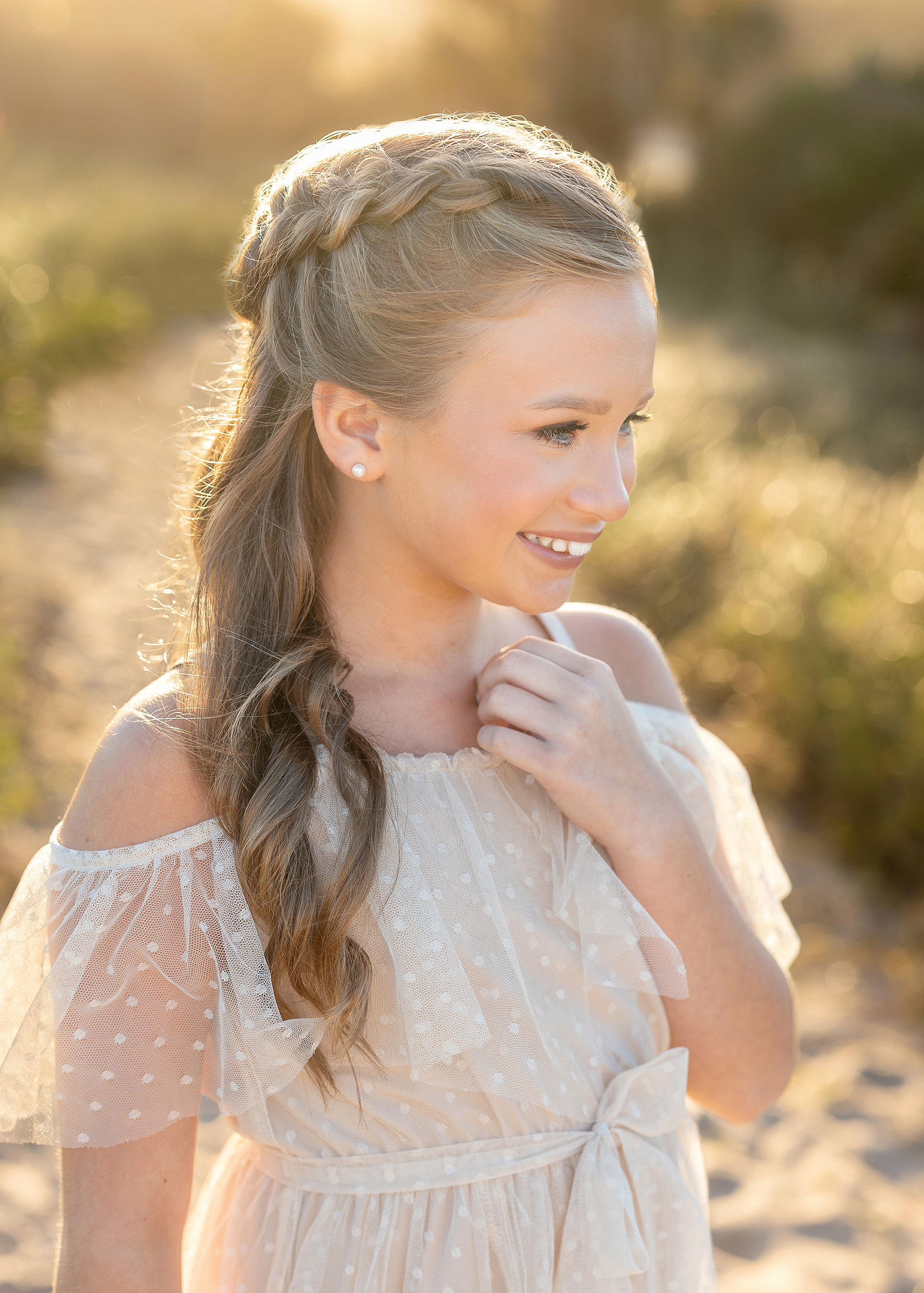 A little girl with a braid in her hair smiles off camera.