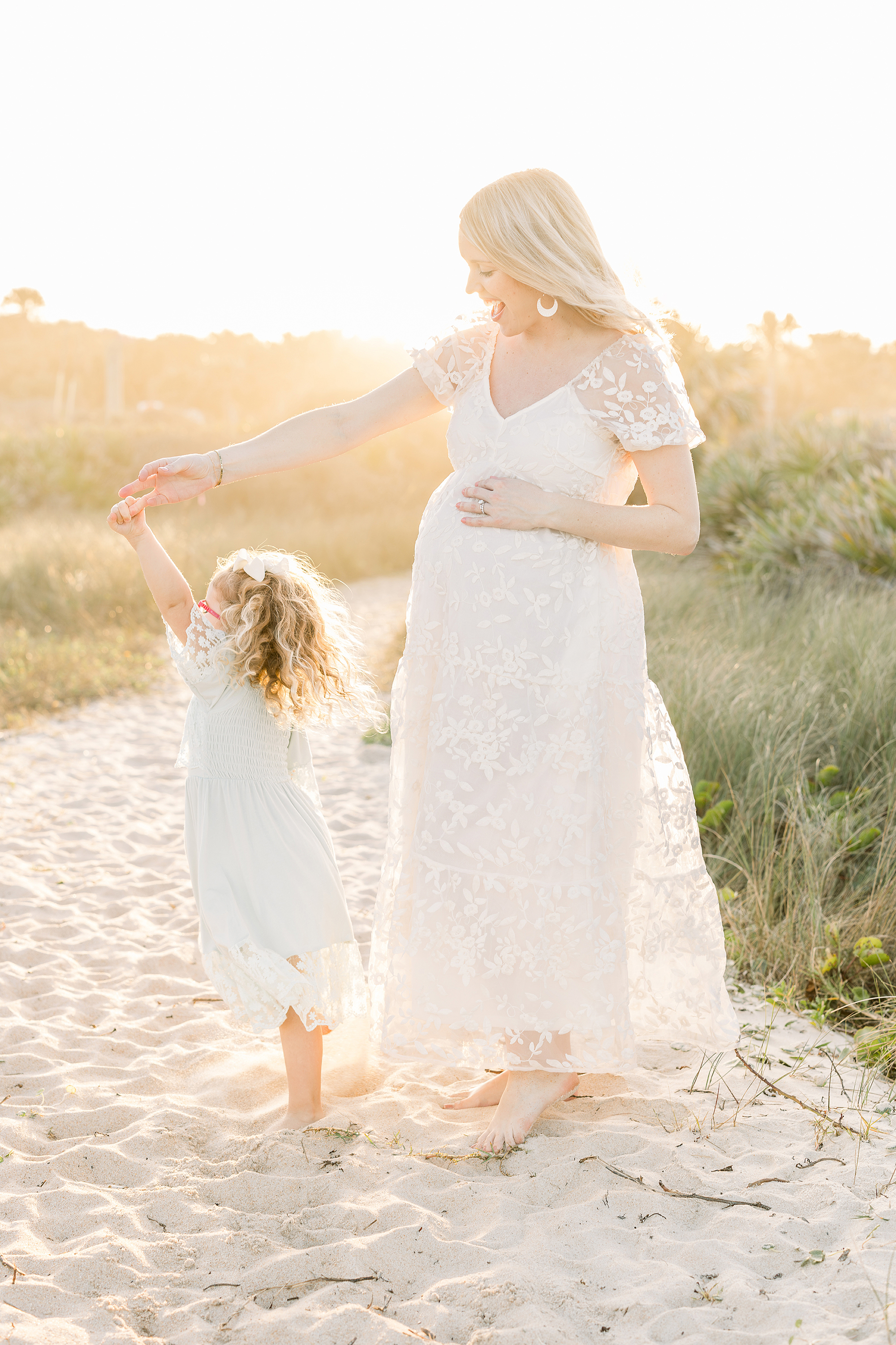 A sunset maternity portrait of a woman and her child on the beach.