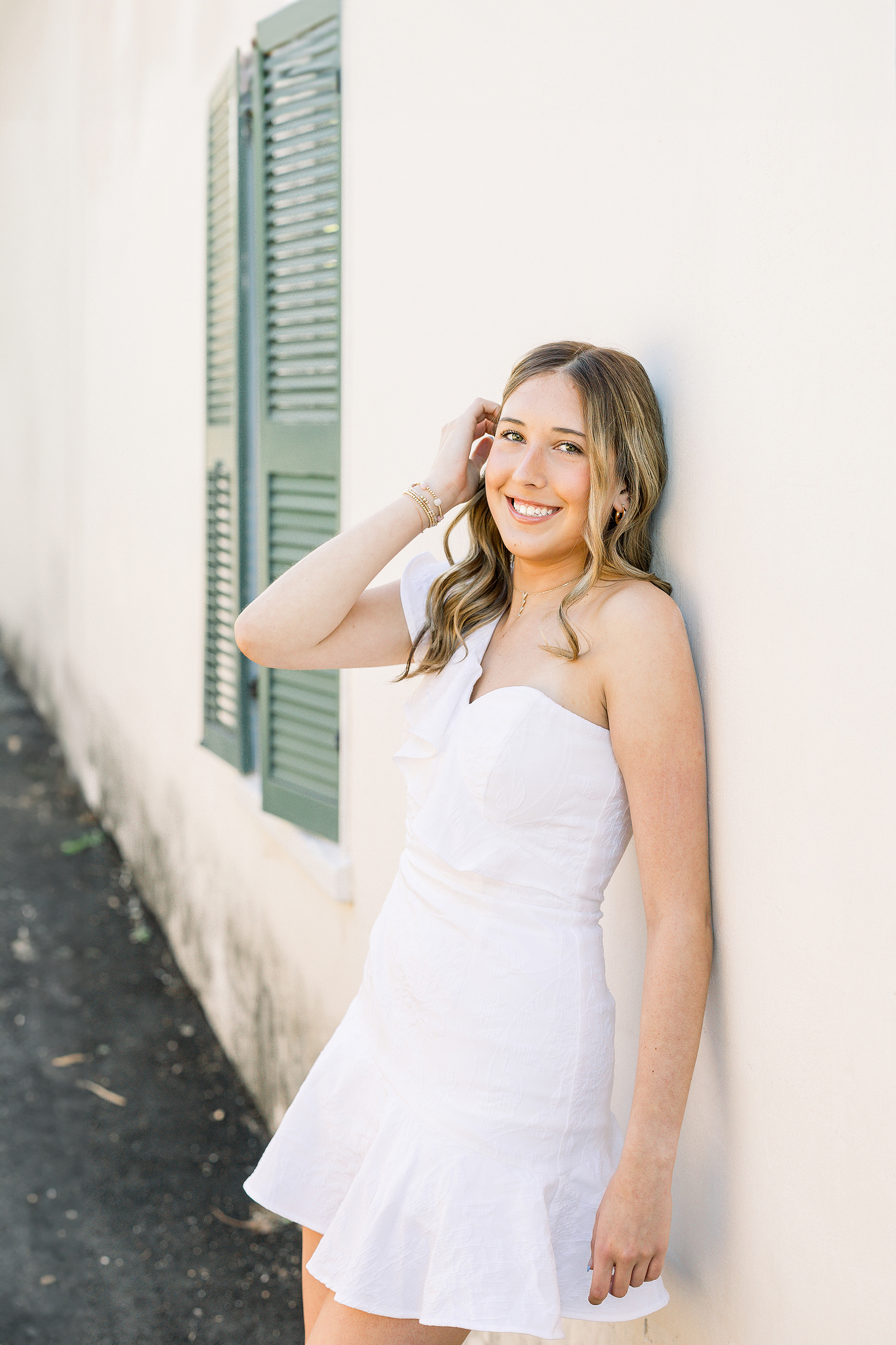 Grad portait of a young woman in a white dress at sunset in downtown St. Augustine.