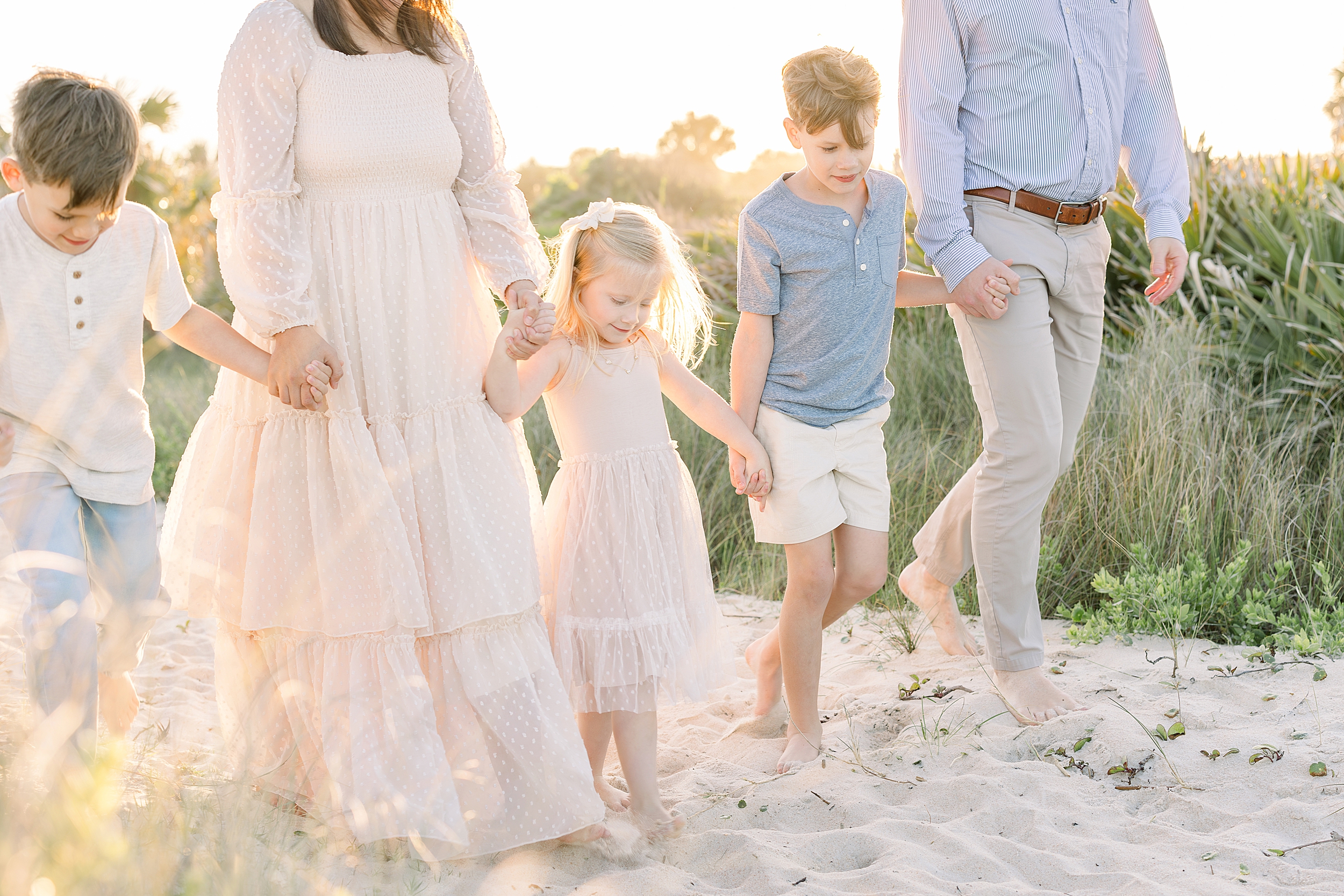 A backlit family portrait of five people walking on the beach at sunset in St. Augustine, Florida.