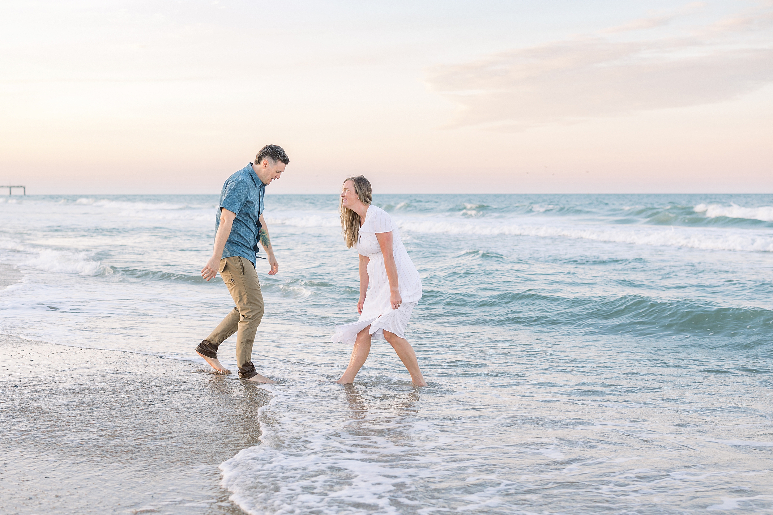 A couple plays together on the beach near the water at sunset on St. Augustine Beach.