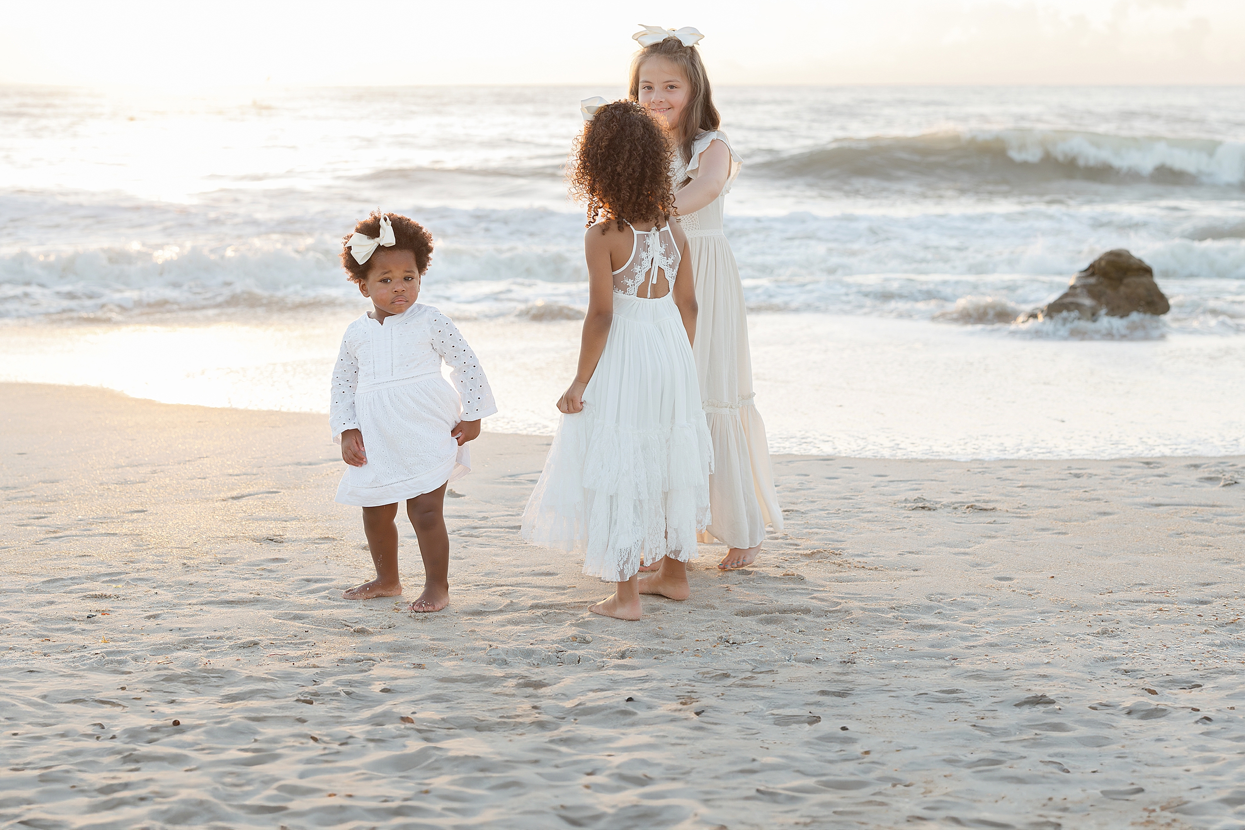 A light and airy sunrise family portrait of three little girls dressed in white.