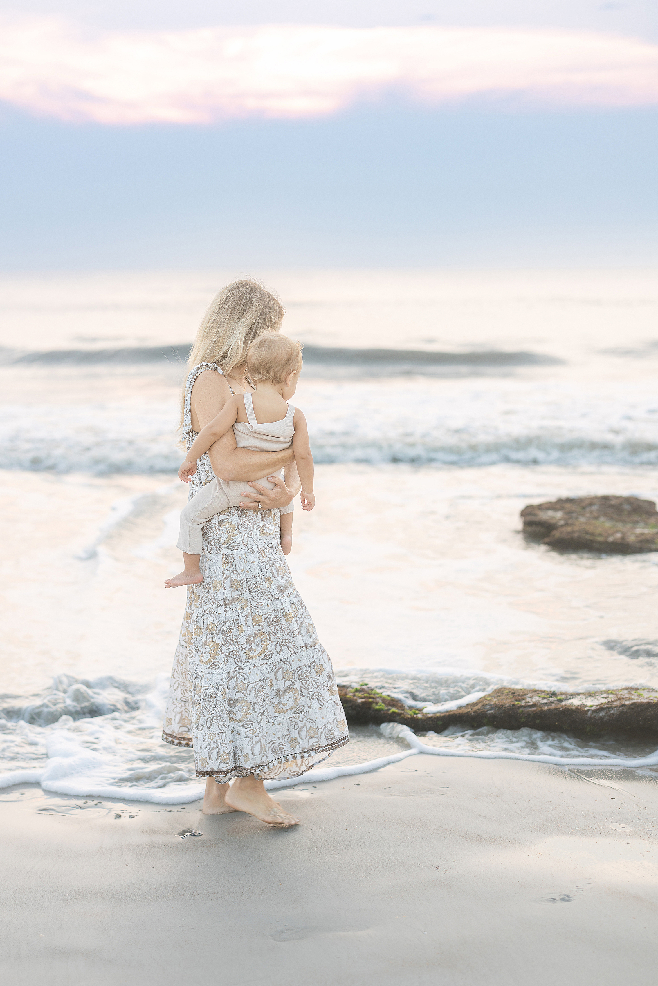 A hazy pastel sunrise motherhood portrait on St. Augustine Beach.