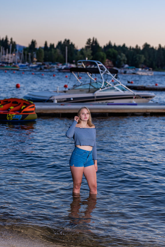 girl senior year photo in lake in front of boat in McCall, Idaho
