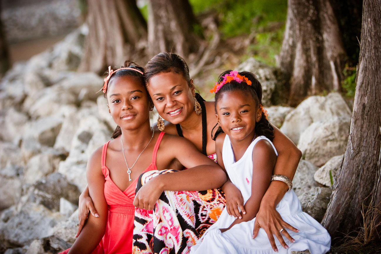 Three women sitting happily on rocks by a lake