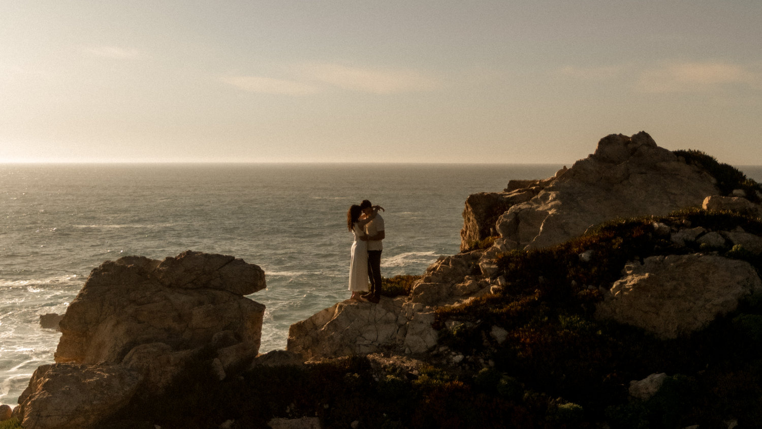 Couple standing on rocks by the ocean