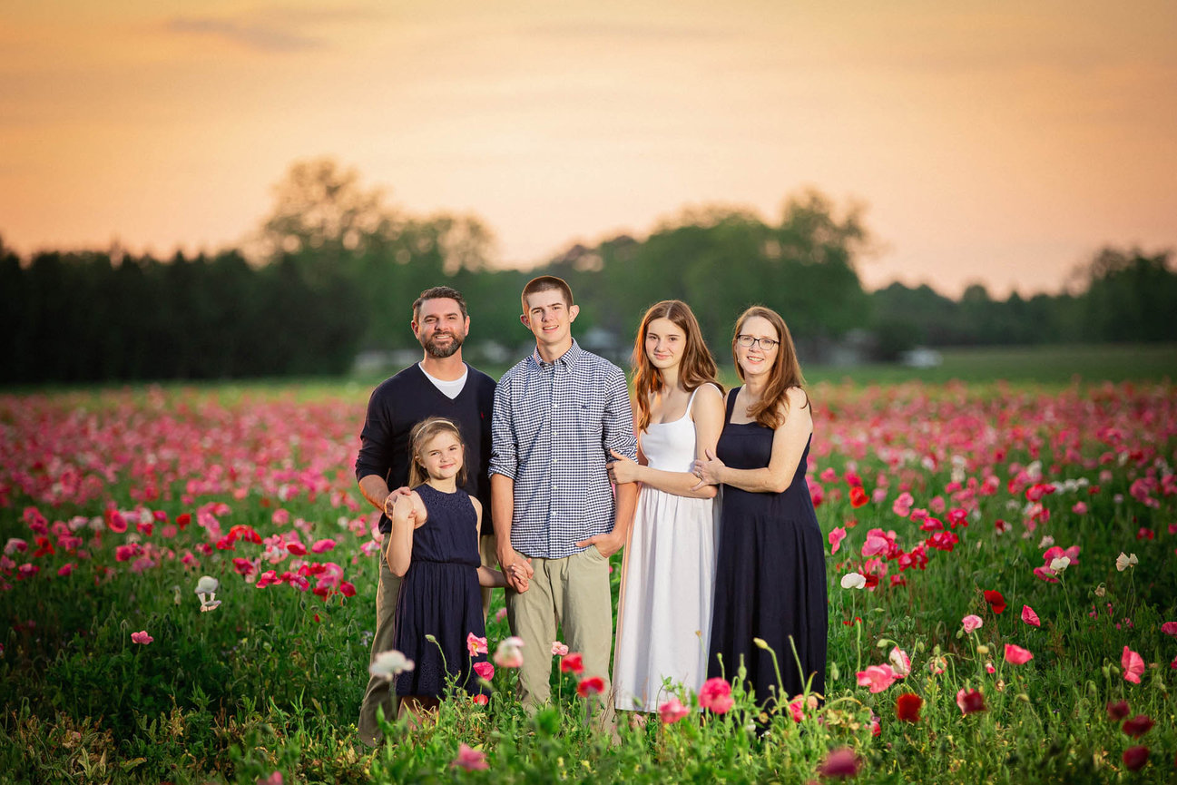 Family portrait in a blooming flower field, showcasing joyful connection in an organic, fine art setting.