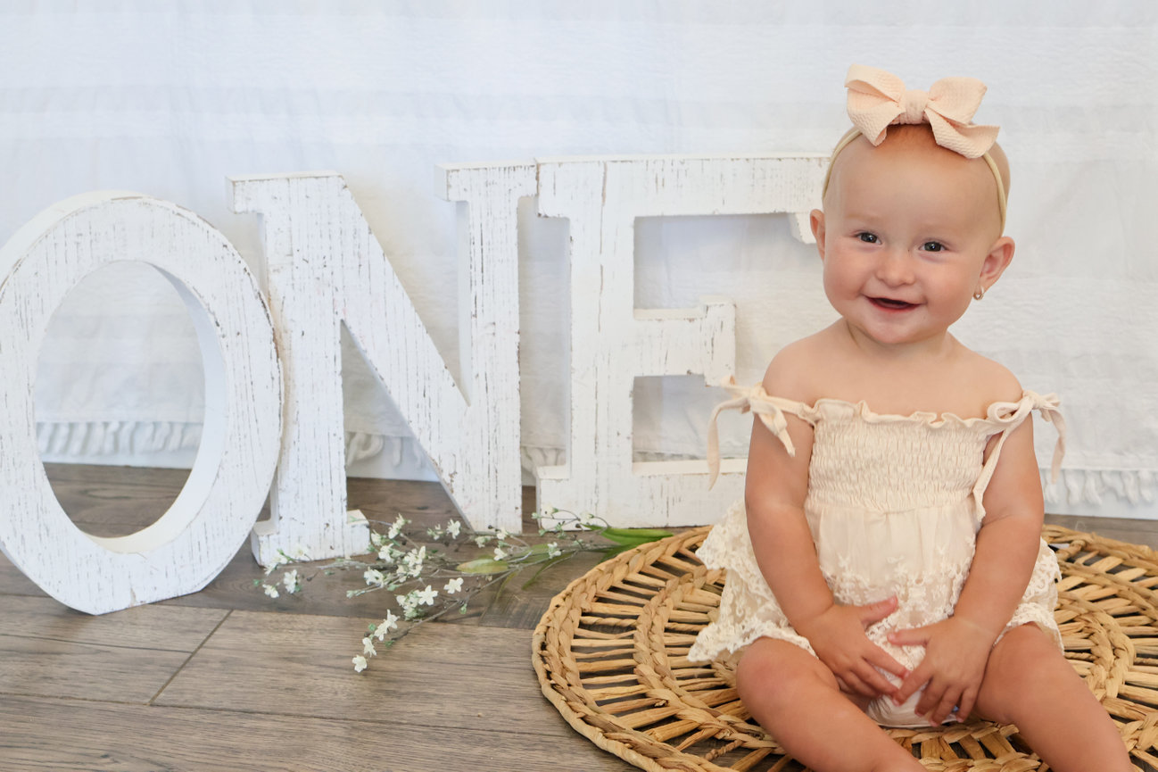 Happy baby sitting next to large white ONE letters