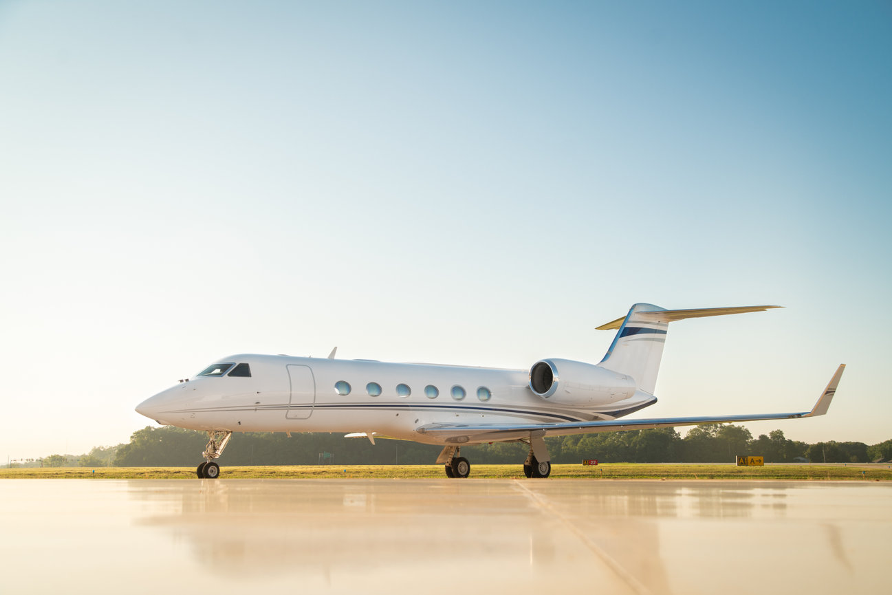 Private jet on a runway under a clear blue sky.