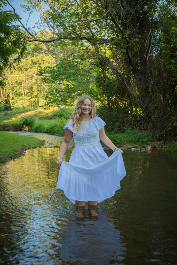 Woman in a white dress standing in a creek